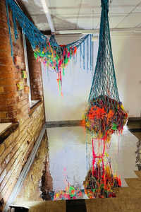 Wool installation hanging from the ceiling using a rainbow of coloured wool