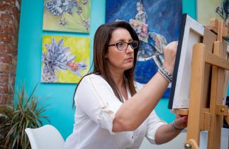 Sarah Perkins at an easel painting in her studio